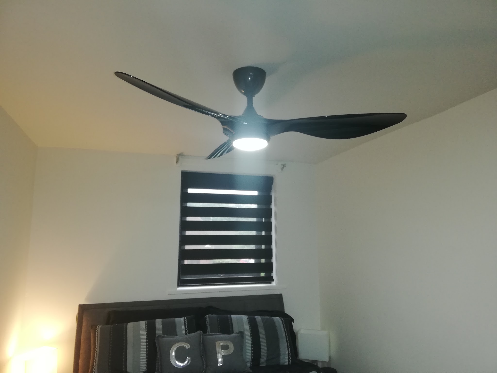 A black ceiling fan with an integrated light in a bedroom