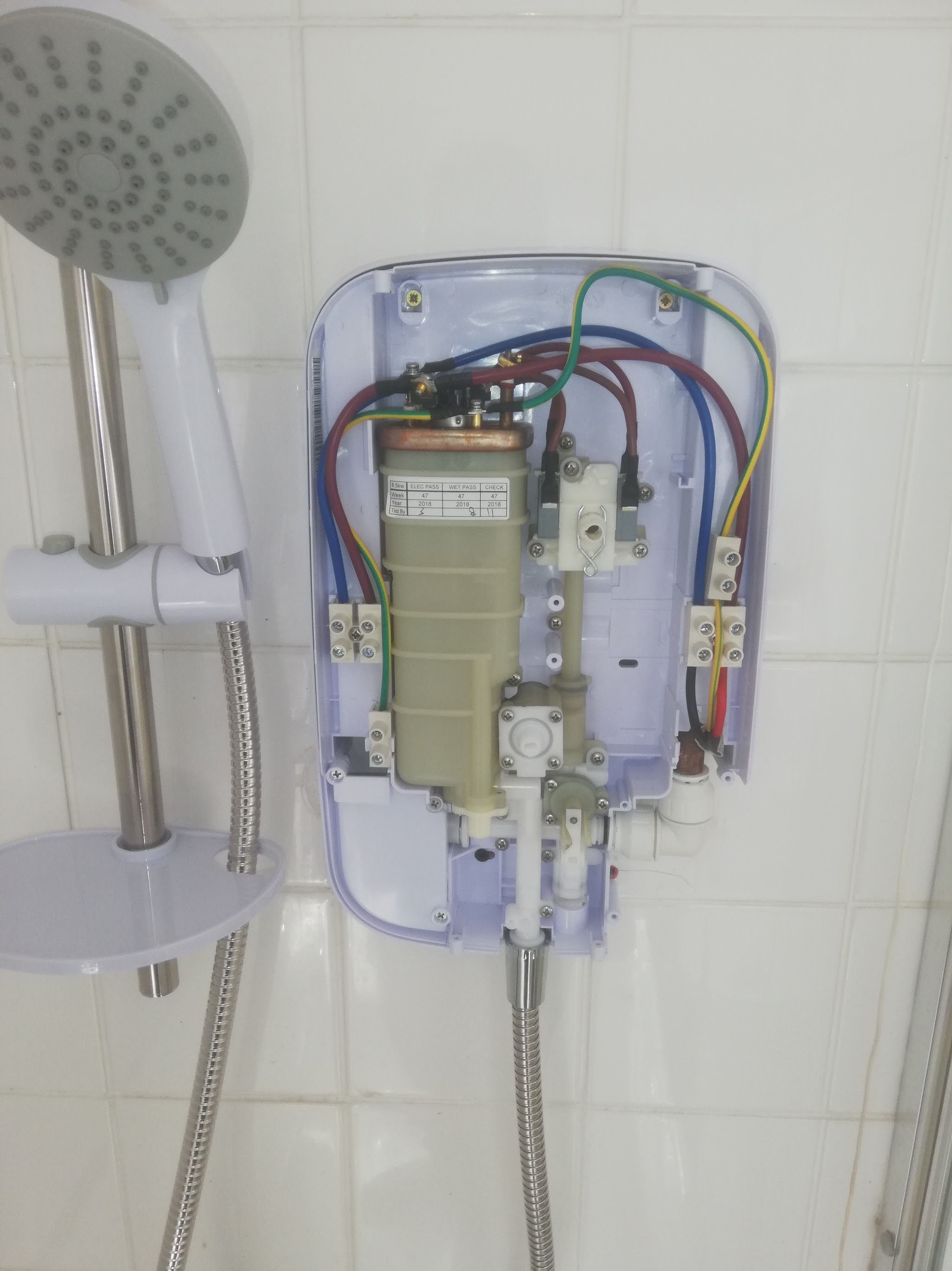 An electric shower with its cover off during installation